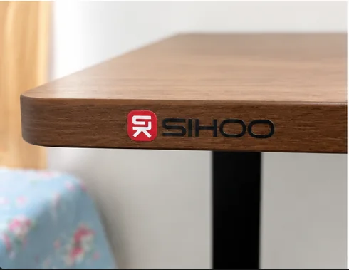 Close-up of the SIHOO logo on the walnut edge of my standing desk