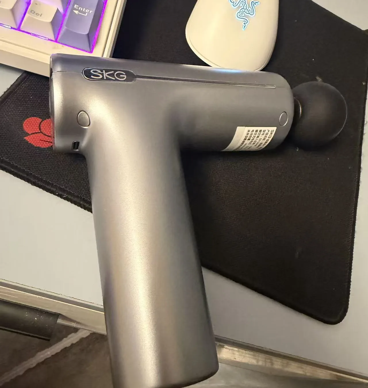 SKG F1 massage gun held in hand with the round ball head attached