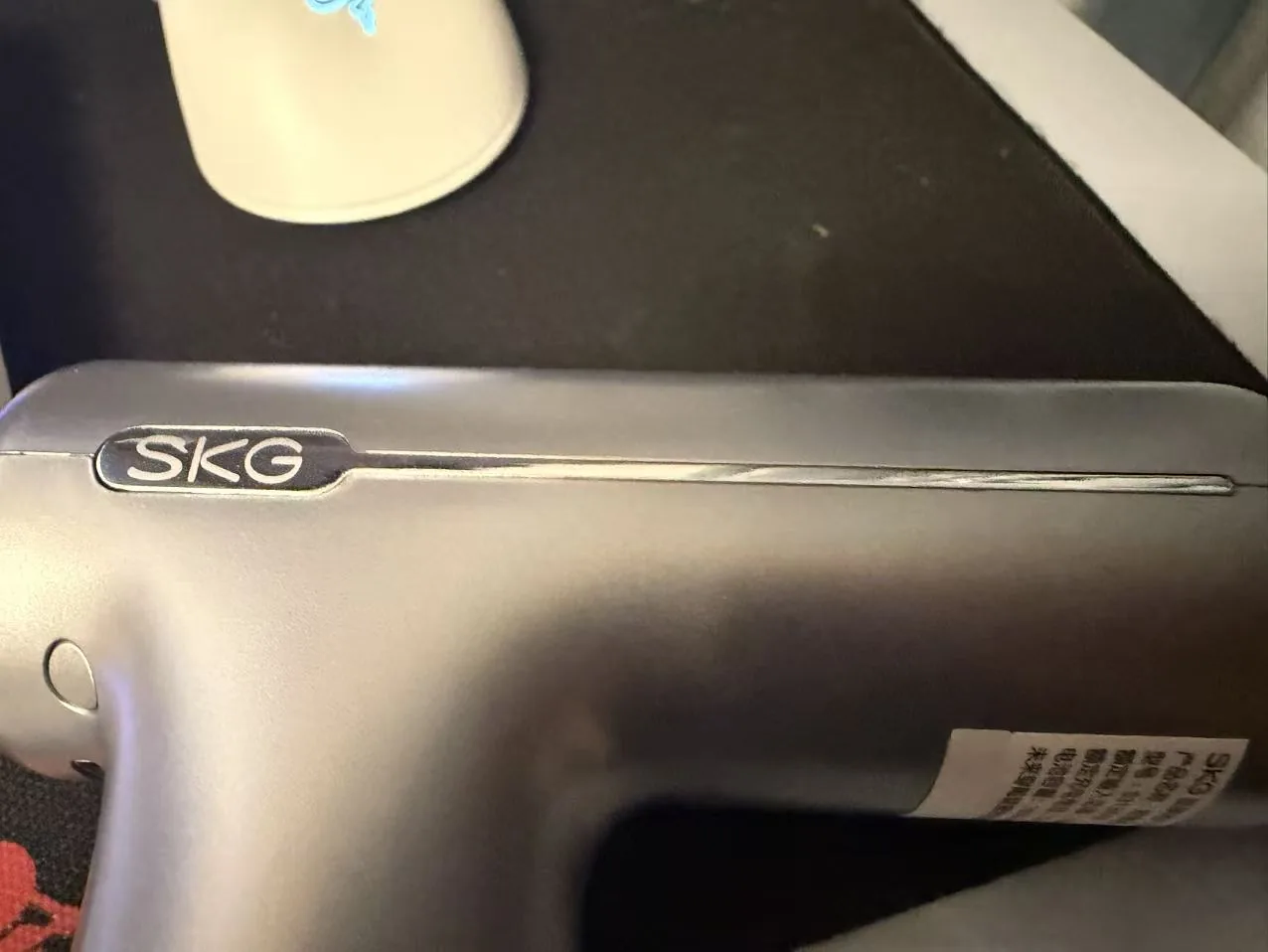 Close-up of the SKG logo badge on the body of the F1 massage gun