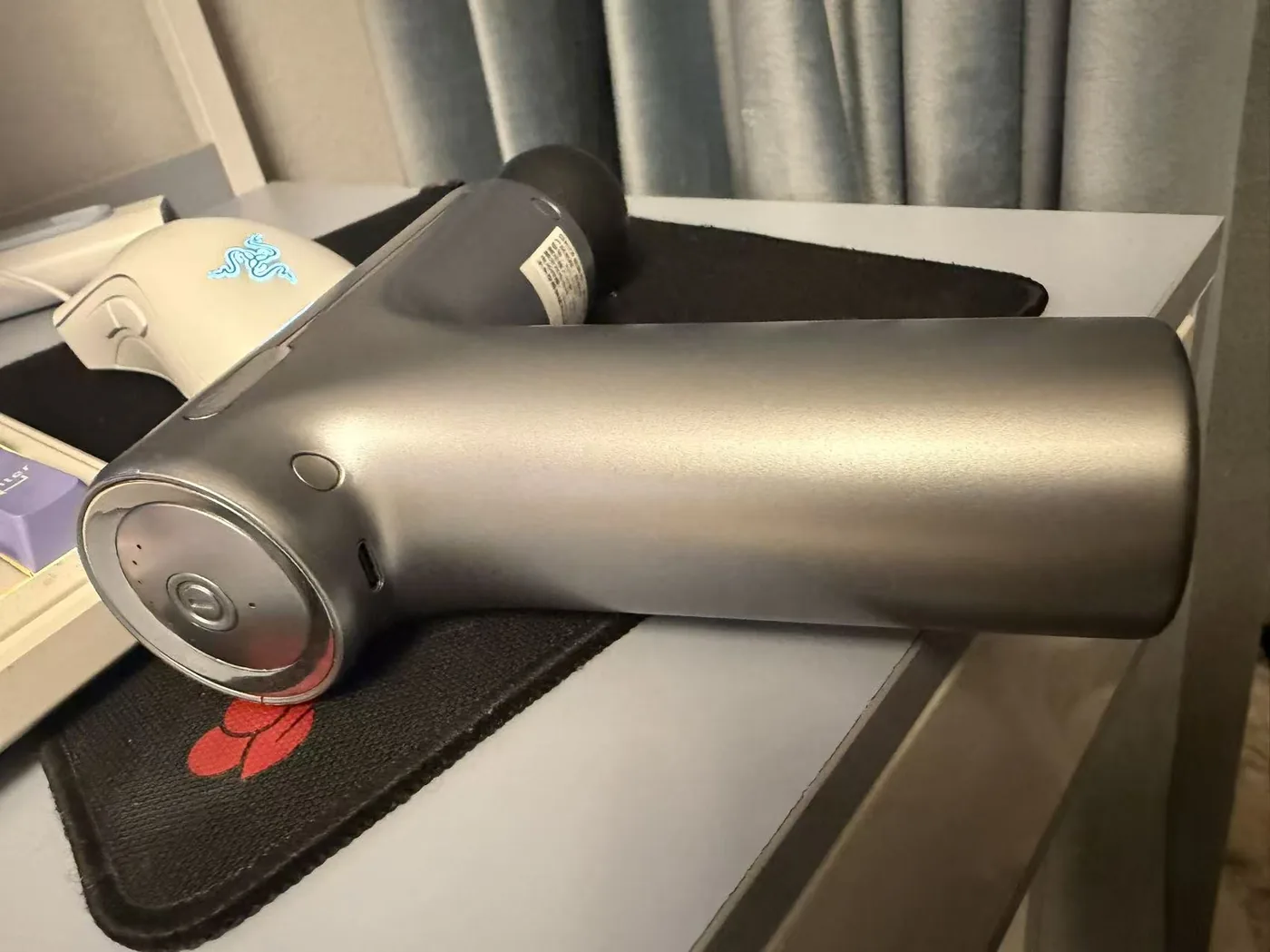 Side view of the SKG F1 showing the round control at the base, USB-C charging port, and ball head
