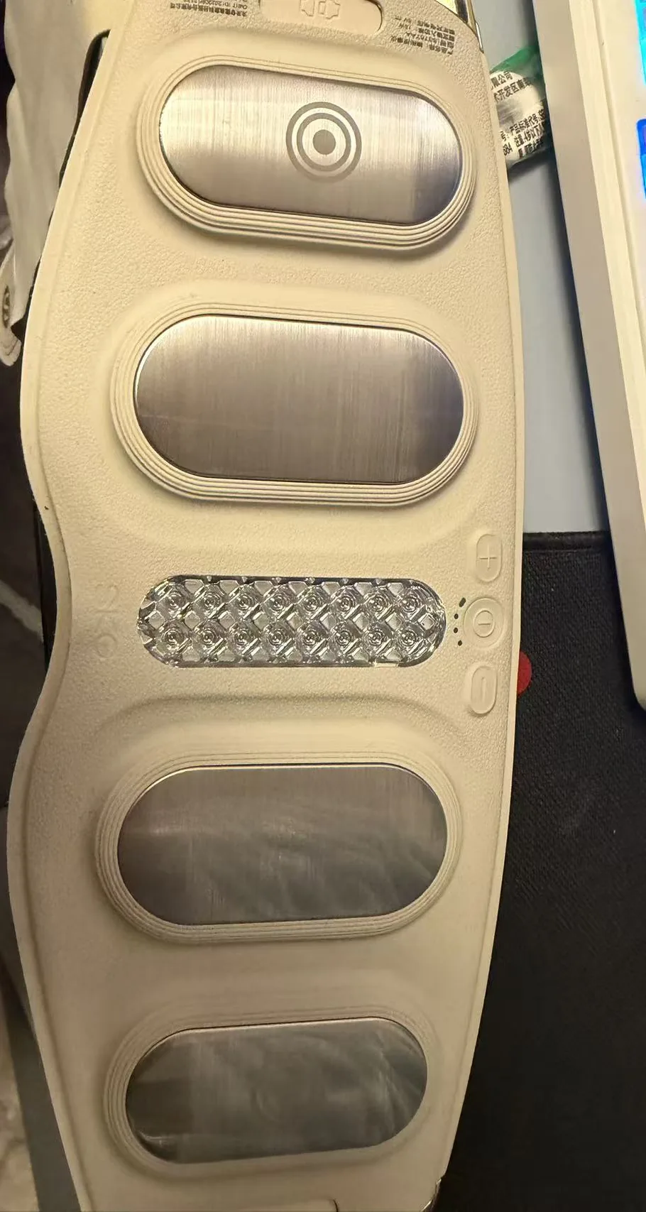 Inner side of the SKG G5 with four brushed-metal EMS pads, a central heat window, and plus, mode and minus buttons